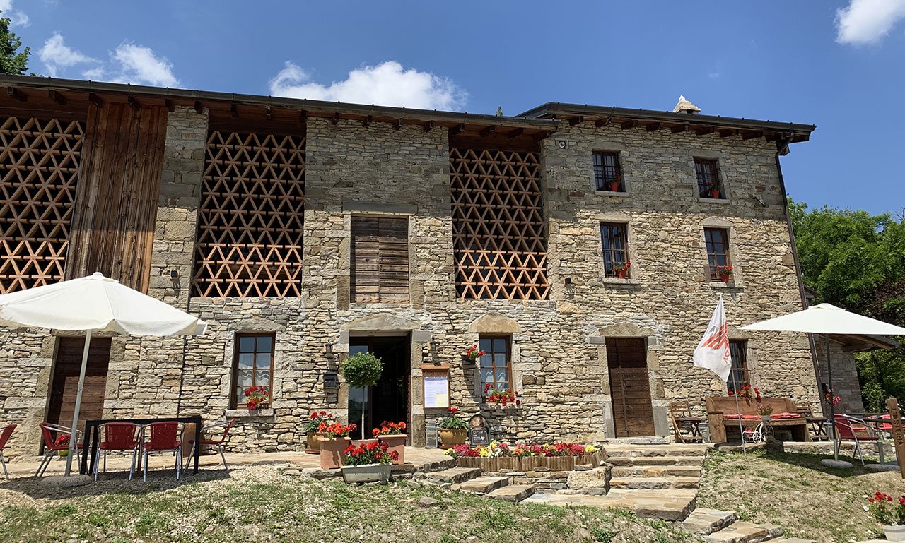 La casa in pietra dell’osteria con i tavoli all’aperto